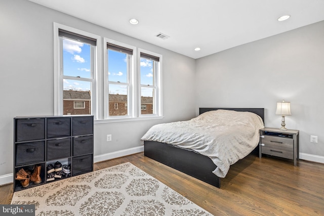 bedroom featuring multiple windows and dark hardwood / wood-style flooring