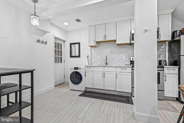 kitchen with washer / dryer, tasteful backsplash, decorative light fixtures, appliances with stainless steel finishes, and white cabinets