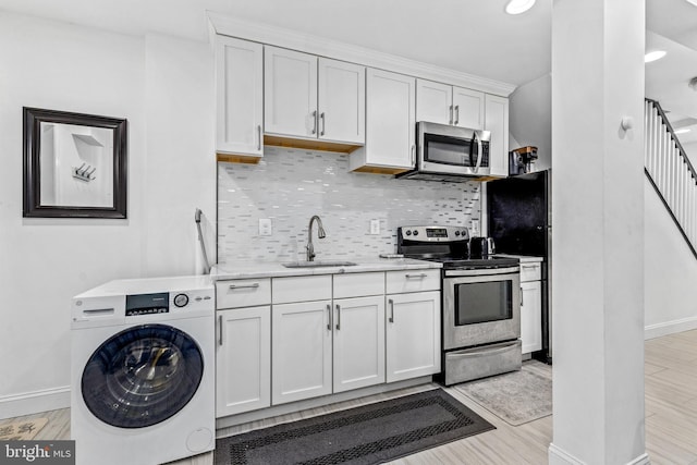 kitchen featuring sink, white cabinetry, stainless steel appliances, tasteful backsplash, and washer / clothes dryer