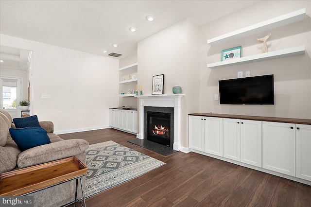 living room featuring built in shelves, dark wood-type flooring, and a high end fireplace