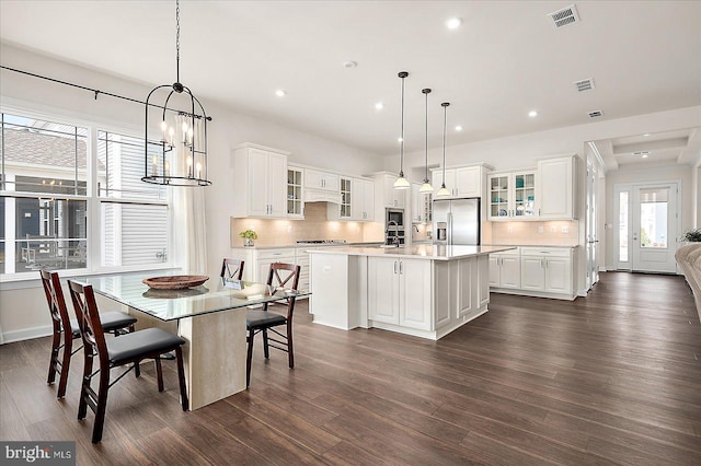 kitchen with white cabinetry, a center island, stainless steel fridge, and decorative light fixtures