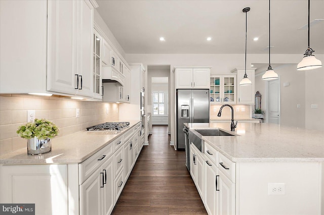 kitchen featuring white cabinetry, appliances with stainless steel finishes, light stone counters, and hanging light fixtures