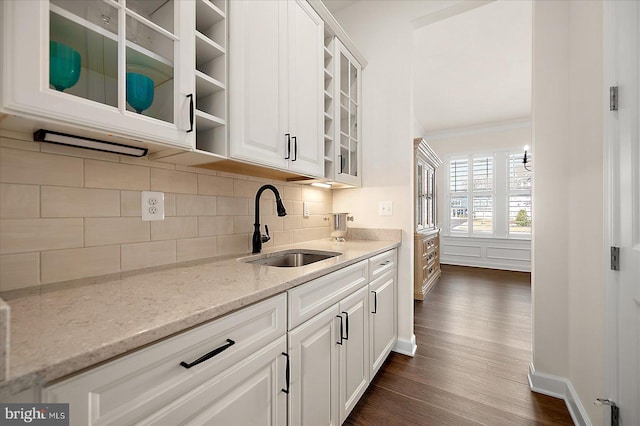 kitchen with white cabinetry, sink, decorative backsplash, light stone counters, and crown molding