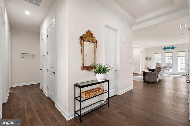 hallway featuring crown molding, dark hardwood / wood-style floors, and a raised ceiling