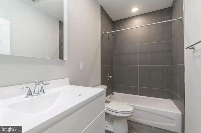 full bathroom featuring tile patterned floors, vanity, tiled shower / bath combo, and toilet