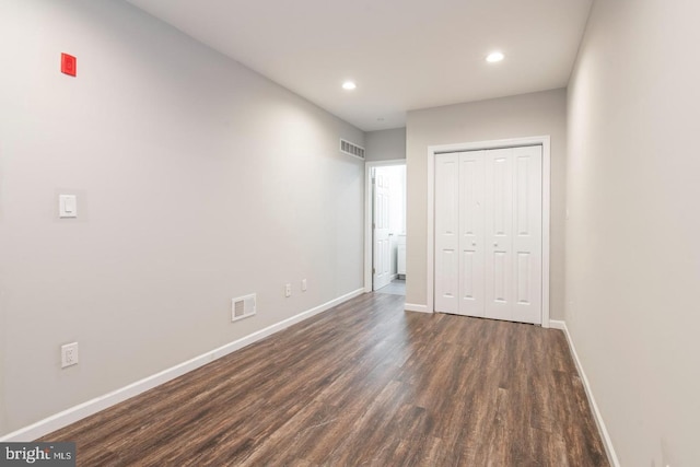 unfurnished bedroom featuring dark hardwood / wood-style flooring and a closet