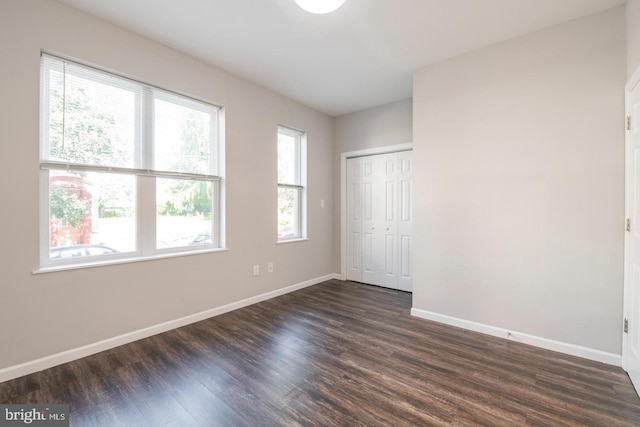 unfurnished bedroom featuring a closet and dark wood-type flooring