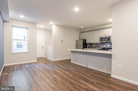 kitchen featuring white fridge, dark hardwood / wood-style flooring, stove, and tasteful backsplash