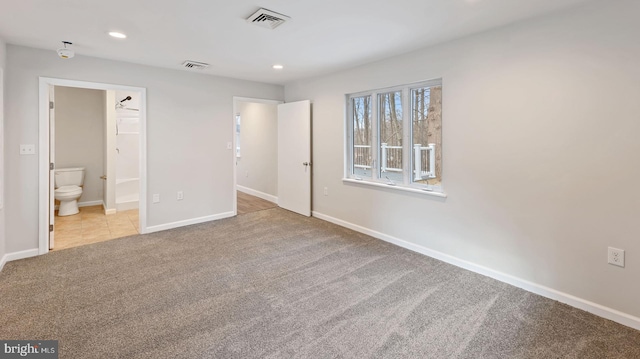 unfurnished bedroom featuring light colored carpet and connected bathroom