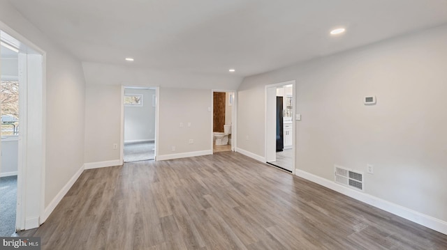 empty room featuring light wood-type flooring and vaulted ceiling