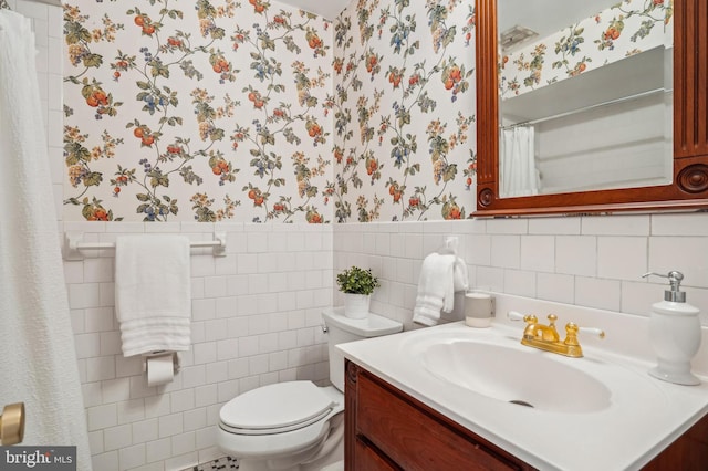 bathroom featuring vanity, tile walls, and toilet