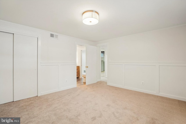 unfurnished bedroom with crown molding, light colored carpet, and a closet