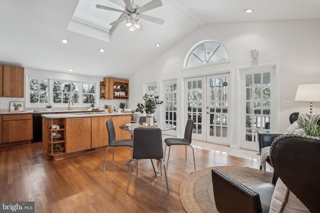 interior space featuring french doors, a skylight, high vaulted ceiling, black dishwasher, and hardwood / wood-style flooring