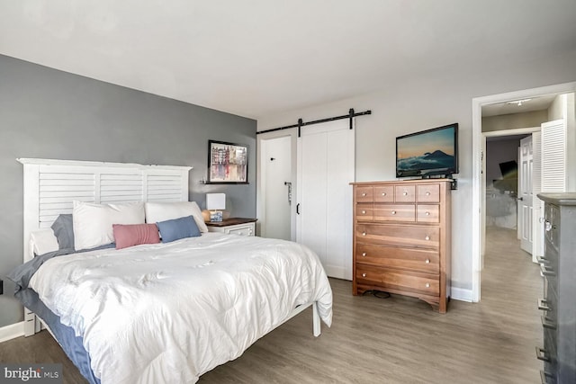 bedroom with hardwood / wood-style floors and a barn door