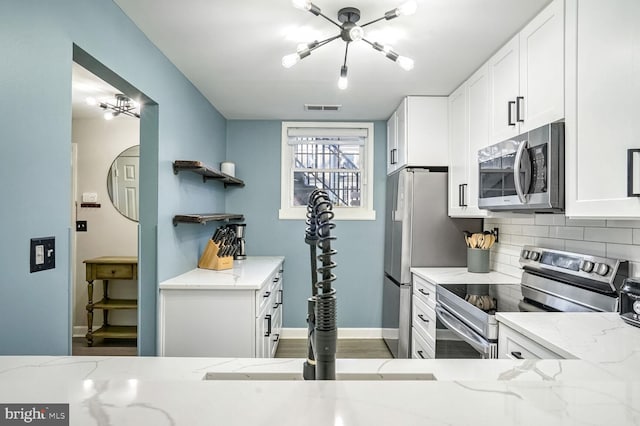 kitchen with white cabinetry, appliances with stainless steel finishes, decorative backsplash, and light stone counters