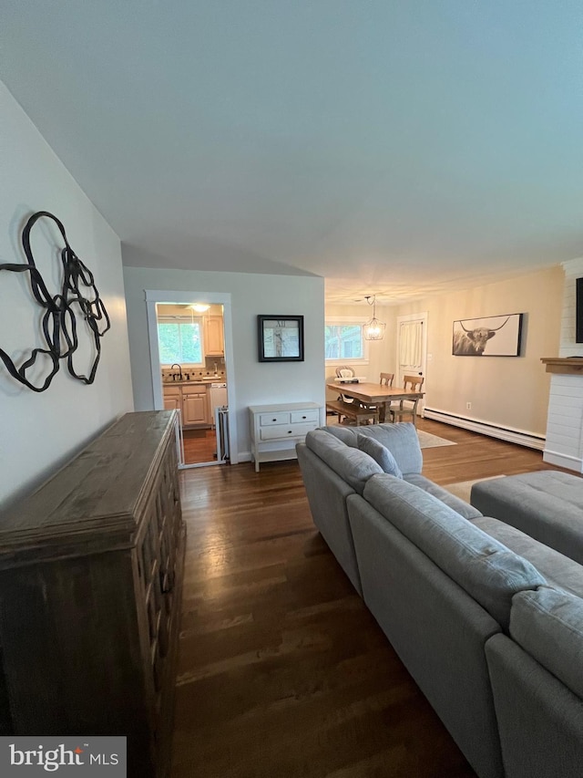 living room with an inviting chandelier, a baseboard heating unit, dark wood-type flooring, and sink