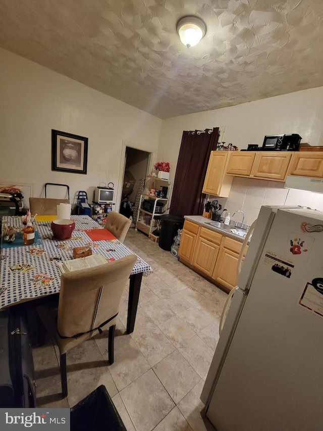 kitchen featuring sink, white fridge, a textured ceiling, light brown cabinetry, and light tile patterned floors