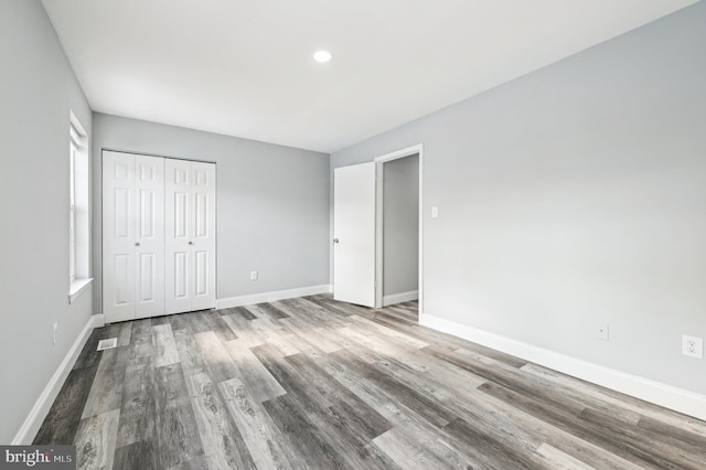 unfurnished bedroom featuring hardwood / wood-style floors and a closet