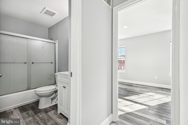 full bathroom with combined bath / shower with glass door, vanity, hardwood / wood-style flooring, and toilet