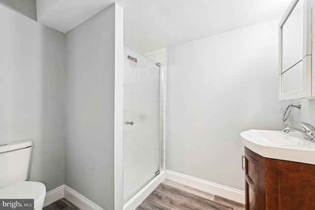 bathroom with walk in shower, hardwood / wood-style flooring, vanity, and toilet