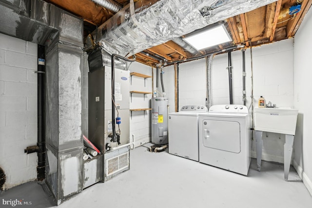 basement featuring electric water heater, washing machine and dryer, and sink