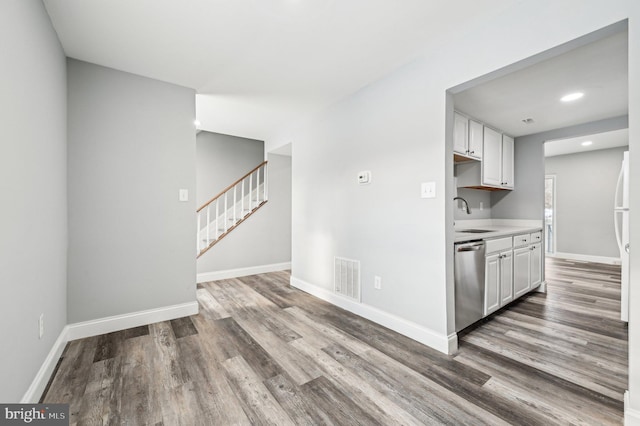 kitchen featuring white cabinets, hardwood / wood-style floors, stainless steel dishwasher, and sink