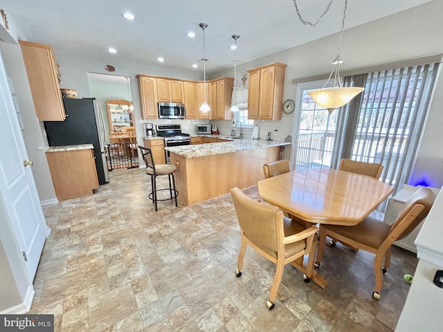 kitchen featuring a kitchen breakfast bar, kitchen peninsula, stainless steel appliances, and decorative light fixtures