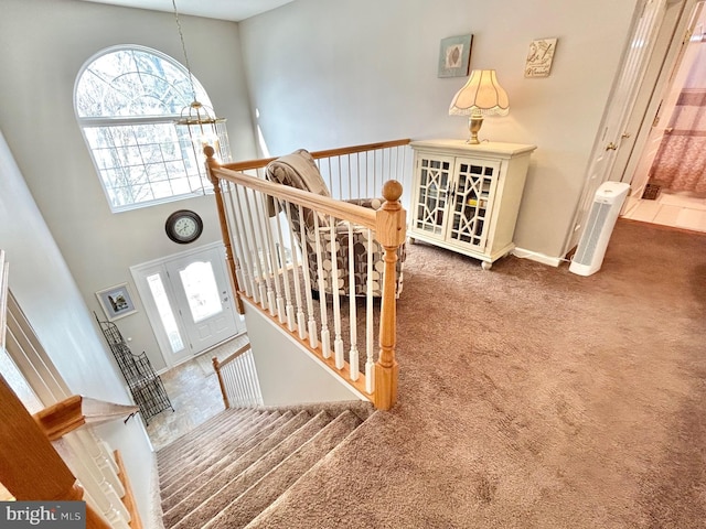 staircase with carpet flooring, a towering ceiling, and a chandelier