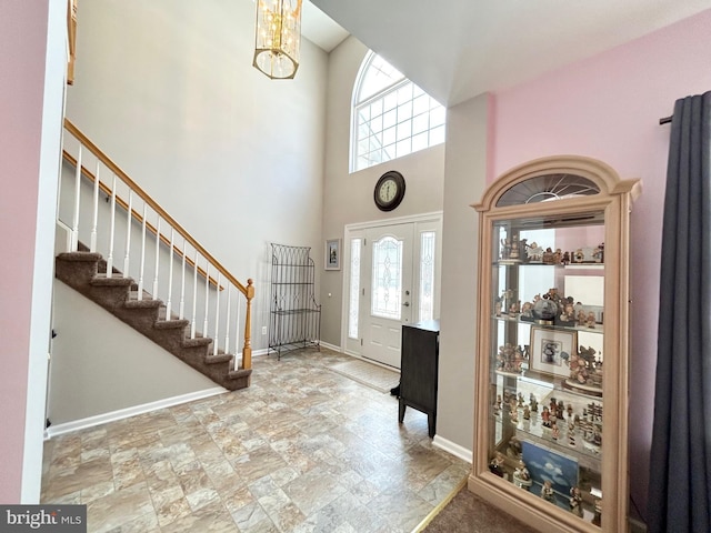 foyer featuring a healthy amount of sunlight, a high ceiling, and an inviting chandelier