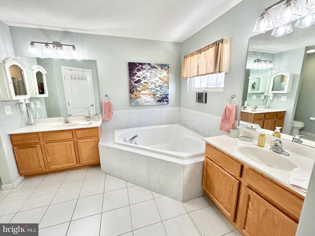 bathroom featuring tile patterned floors, tiled tub, vanity, and toilet