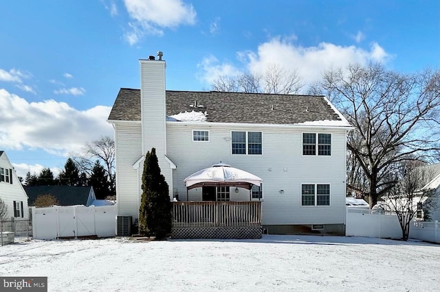 snow covered back of property with a deck