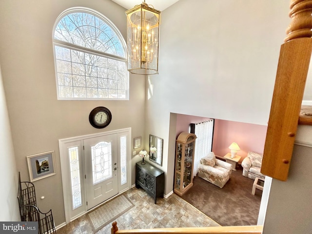 carpeted foyer with a notable chandelier and a high ceiling