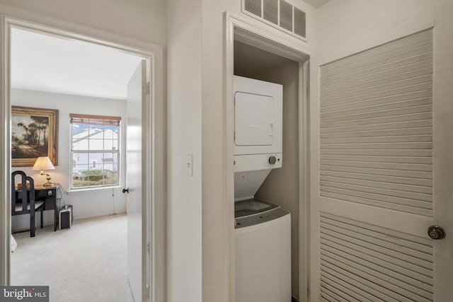 laundry room with light carpet and stacked washer and dryer