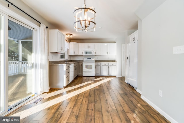 kitchen featuring sink, white cabinetry, pendant lighting, white appliances, and hardwood / wood-style floors