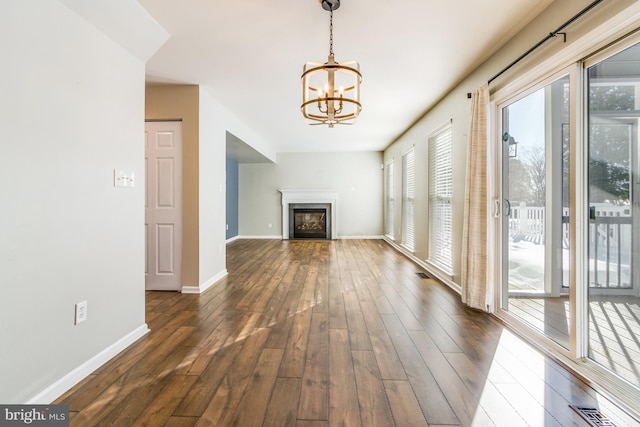 unfurnished living room with an inviting chandelier and dark hardwood / wood-style flooring