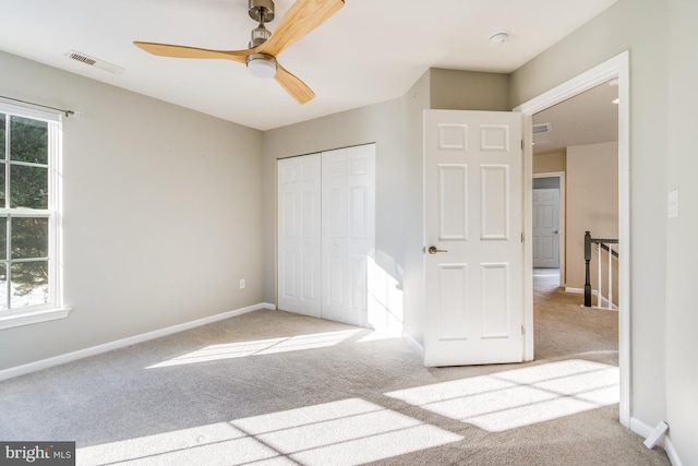 unfurnished bedroom featuring light colored carpet, ceiling fan, and a closet