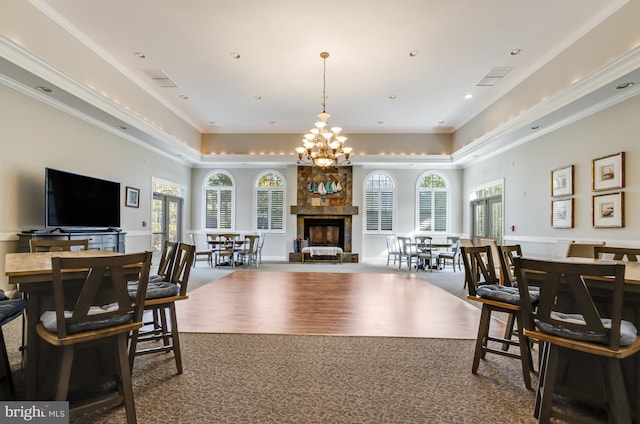 carpeted dining area with a multi sided fireplace, ornamental molding, a notable chandelier, and a wealth of natural light