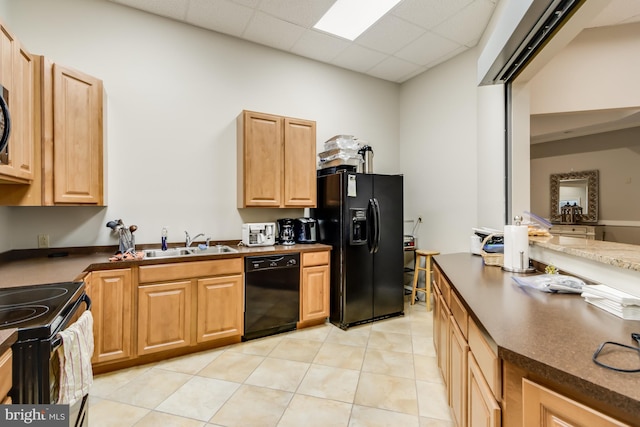 kitchen featuring a paneled ceiling, light tile patterned floors, sink, and black appliances