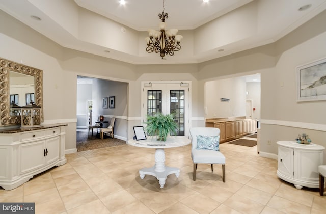 sitting room featuring french doors, an inviting chandelier, light tile patterned floors, ornamental molding, and a high ceiling