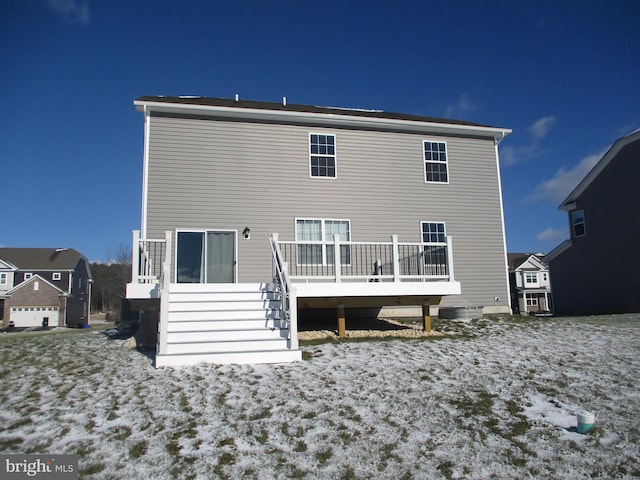 snow covered back of property with a wooden deck