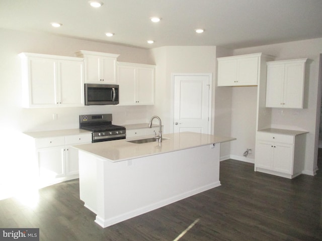 kitchen with appliances with stainless steel finishes, a center island with sink, white cabinetry, and sink