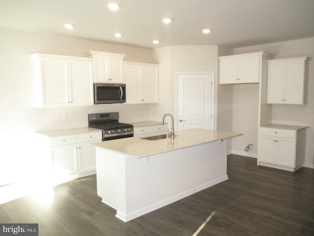 kitchen with white cabinets, sink, appliances with stainless steel finishes, and an island with sink