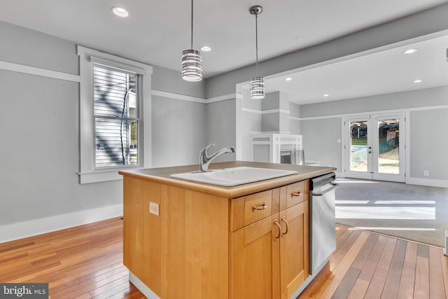 kitchen with sink, a kitchen island with sink, light brown cabinets, light wood-type flooring, and french doors