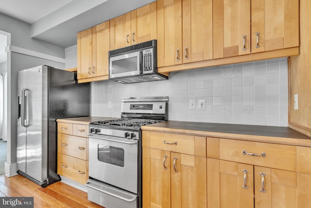 kitchen with appliances with stainless steel finishes, decorative backsplash, and light hardwood / wood-style flooring