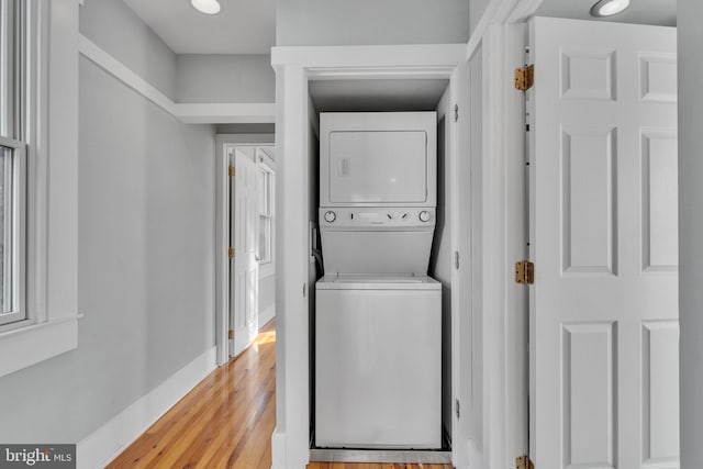 clothes washing area with stacked washer / drying machine and light hardwood / wood-style flooring