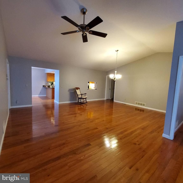 unfurnished living room featuring ceiling fan with notable chandelier, dark hardwood / wood-style flooring, and vaulted ceiling