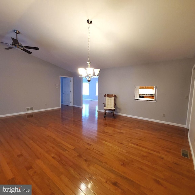 empty room featuring ceiling fan with notable chandelier, dark hardwood / wood-style flooring, and lofted ceiling