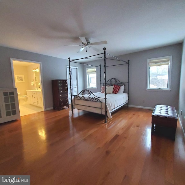 bedroom featuring multiple windows, hardwood / wood-style flooring, ceiling fan, and ensuite bathroom