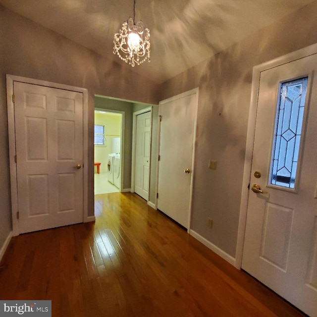 entrance foyer with independent washer and dryer, hardwood / wood-style flooring, and an inviting chandelier