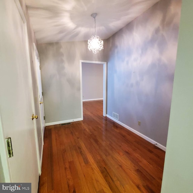 unfurnished dining area featuring dark hardwood / wood-style flooring and an inviting chandelier